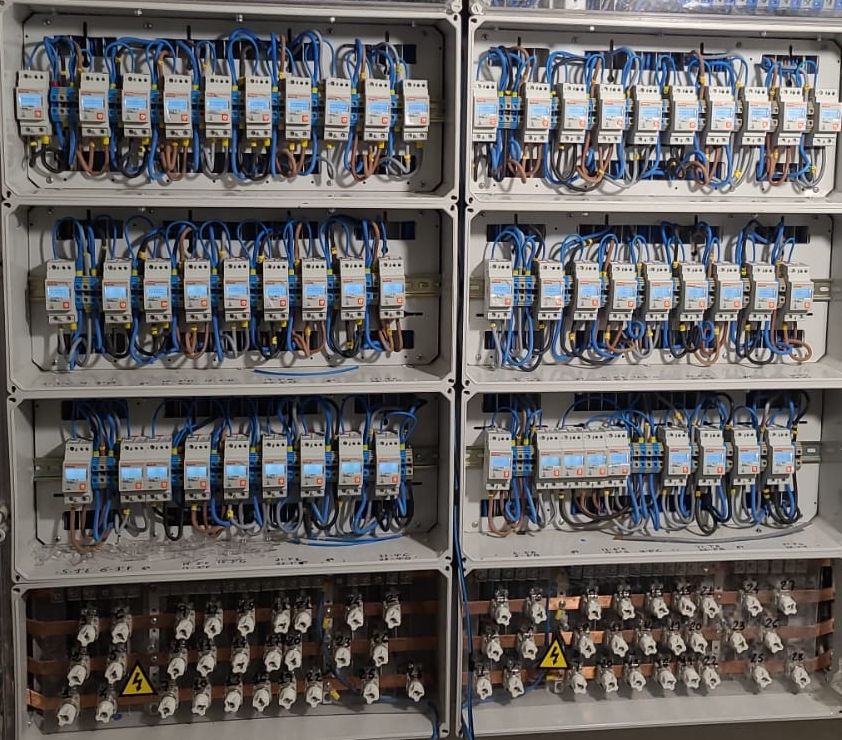 Centralización de contadores eléctricos con los cuadros abiertos: dos columnas con tres filas de contadores en carril cada una, el cableado de cada contador y, debajo, el embarrado de cobre con los fusibles de cada vivienda.